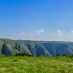 Stunning panoramic view of Meghalaya's lush green hill ranges under a clear blue sky.