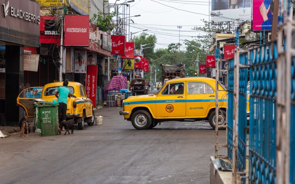 Vibrant street scene in Kolkata featuring classic yellow Ambassador taxis amidst lively urban ambiance.