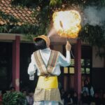 A captivating fire-breathing performance by a young performer in traditional attire in West Java, Indonesia.
