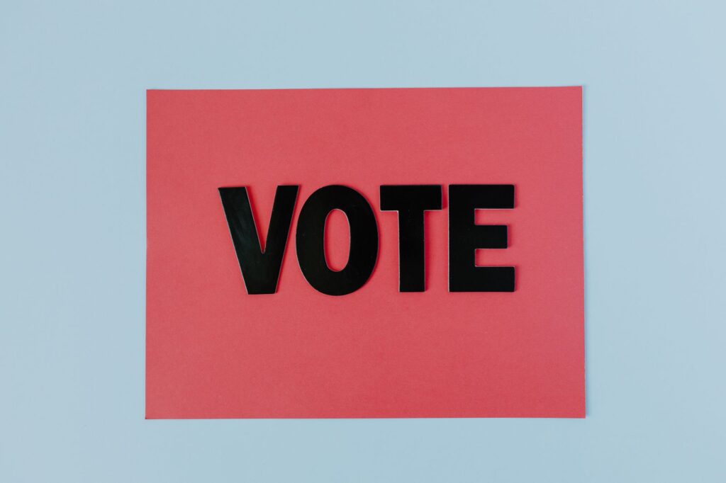 Black letters spelling 'VOTE' on red paper, emphasizing political participation.