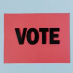 Black letters spelling 'VOTE' on red paper, emphasizing political participation.
