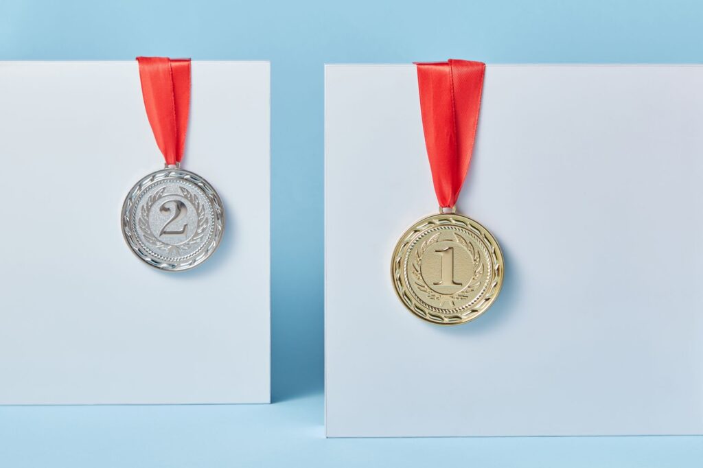 Gold and silver medals with red ribbons against a blue backdrop representing achievement and success.