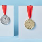 Gold and silver medals with red ribbons against a blue backdrop representing achievement and success.