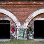Red brick building with graffiti in Warsaw, Poland, showcasing urban art and architecture.