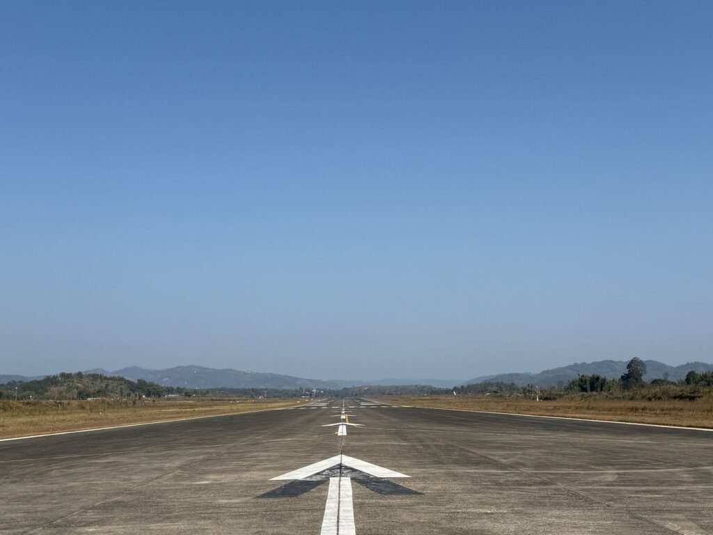 Clear day view of an empty airstrip with mountains in the background, set in Meghalaya, India.