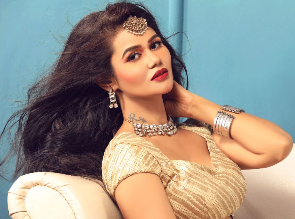 Portrait of a beautiful Indian woman in traditional jewelry posing elegantly indoors.