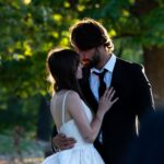 Young couple embracing in a tender moment outdoors with sunlight filtering through trees.