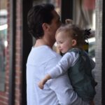 Father holding daughter outdoors, showcasing family bond in a city environment.