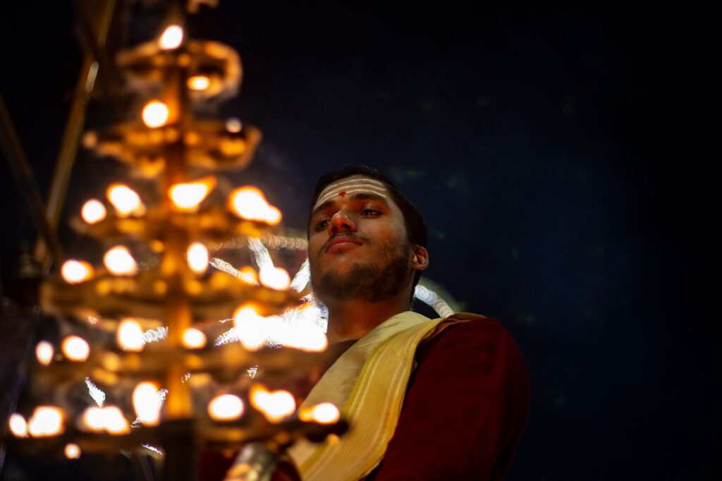 A man performing a traditional Indian candlelight ritual at night in Varanasi, India.