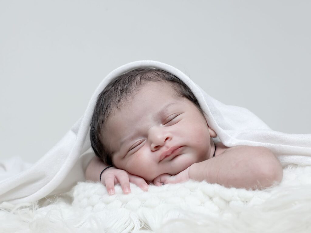 A serene portrait of a newborn baby sleeping in a cozy white blanket.