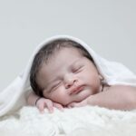 A serene portrait of a newborn baby sleeping in a cozy white blanket.