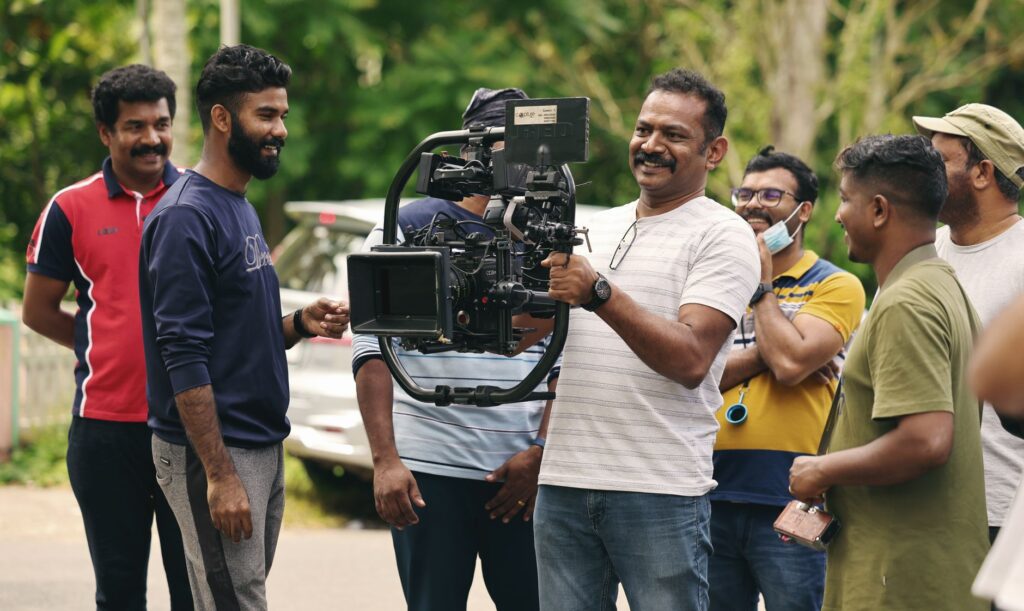 Group of men filming with a professional camera outdoors, capturing a joyful moment.