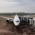 A modern jet airplane docked at an airport terminal gate, ready for boarding on a cloudy day.