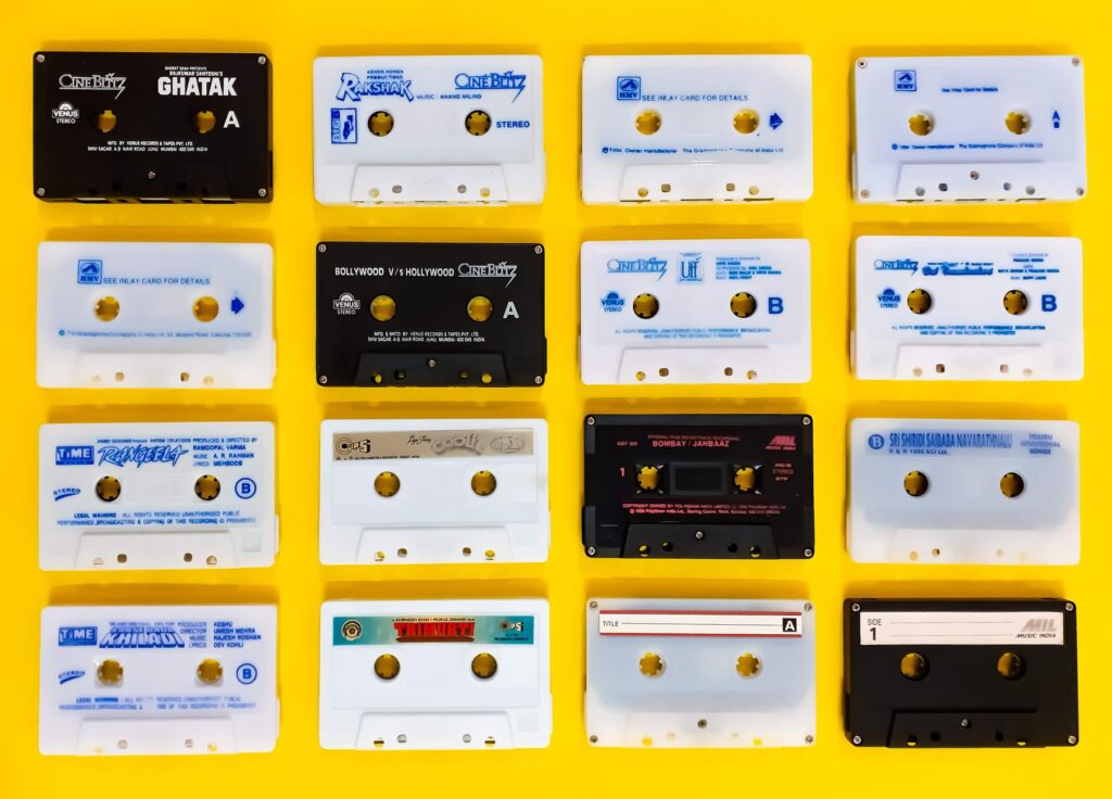 A collection of retro cassette tapes arranged on a vibrant yellow background.