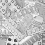 Monochrome close-up of assorted blister packs with pills, highlighting pharmaceutical packaging.