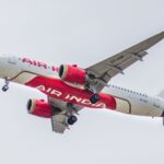 A close-up shot of an Air India airplane flying in the sky, showcasing its design and flight details.