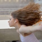 Captivating side view of a young woman wearing wireless earbuds, caught in motion.