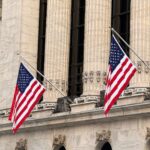 American flags displayed prominently on a historic Wall Street building in New York City.