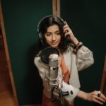 Professional female musician recording vocals in a music studio.