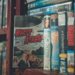 A nostalgic display of vintage VHS tapes with classic movie titles on a wooden shelf indoors.