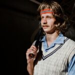 Portrait of a retro-styled tennis player with a racquet and headband, evoking a 70s vibe.