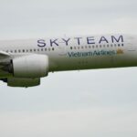 A Vietnam Airlines plane in SkyTeam livery flying in clear sky, showcasing its underbelly and landing gear.