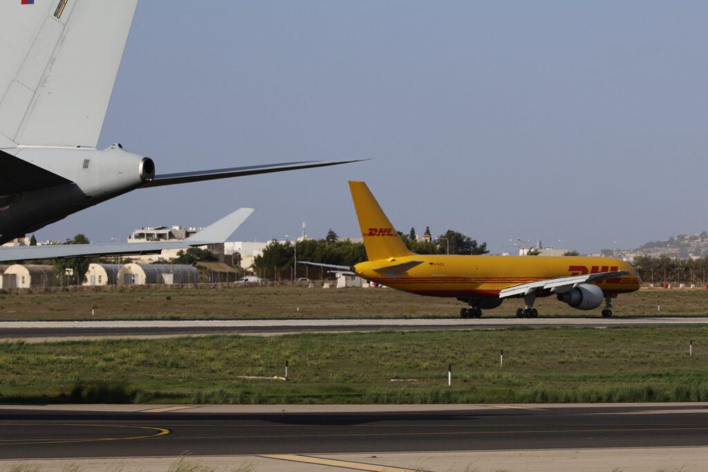 A DHL cargo plane taxiing on an airport runway during daylight.