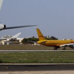 A DHL cargo plane taxiing on an airport runway during daylight.