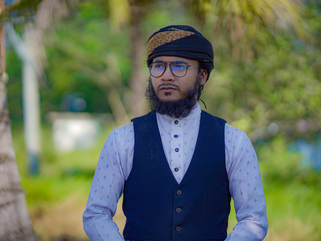 Elegant portrait of a bearded man wearing a turban and vest outdoors in Noakhali, Bangladesh.