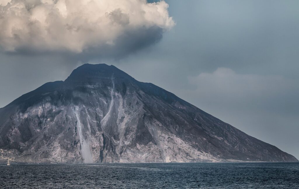 Serene view of Stromboli volcano in Sicily with clouds above and calm seas below.