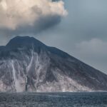 Serene view of Stromboli volcano in Sicily with clouds above and calm seas below.
