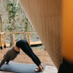 Woman practicing yoga outdoors in a tent, emphasizing relaxation and fitness.