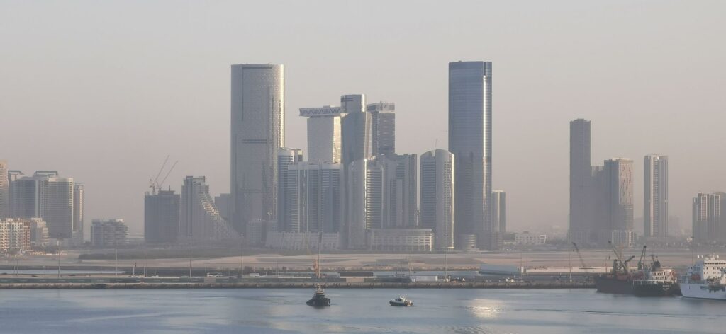 Panoramic view of Abu Dhabi's futuristic skyline with modern skyscrapers under hazy skies.