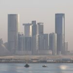 Panoramic view of Abu Dhabi's futuristic skyline with modern skyscrapers under hazy skies.