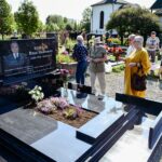 Visitors at a cemetery memorial site, paying respects to the deceased.