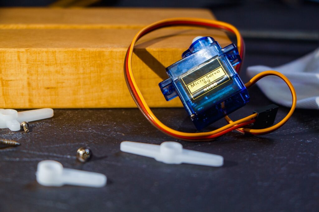 Close-up of a micro servo motor and components for robotics assembly.