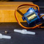 Close-up of a micro servo motor and components for robotics assembly.