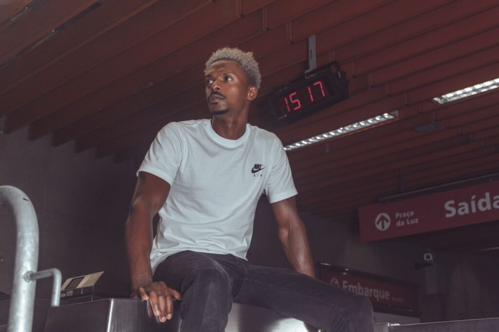 Young man in casual attire looking contemplatively at a subway entrance.