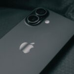 Detailed close-up of a modern smartphone on a textured dark fabric background.