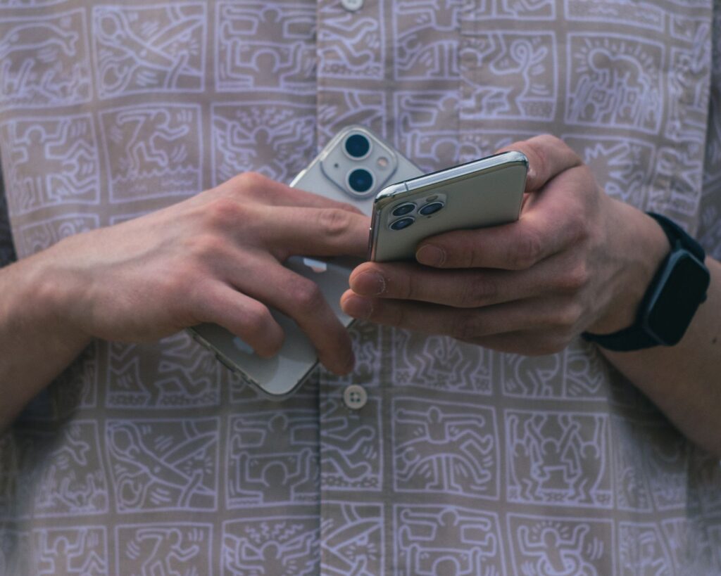 Detail of hands holding two smartphones, showcasing modern technology usage.