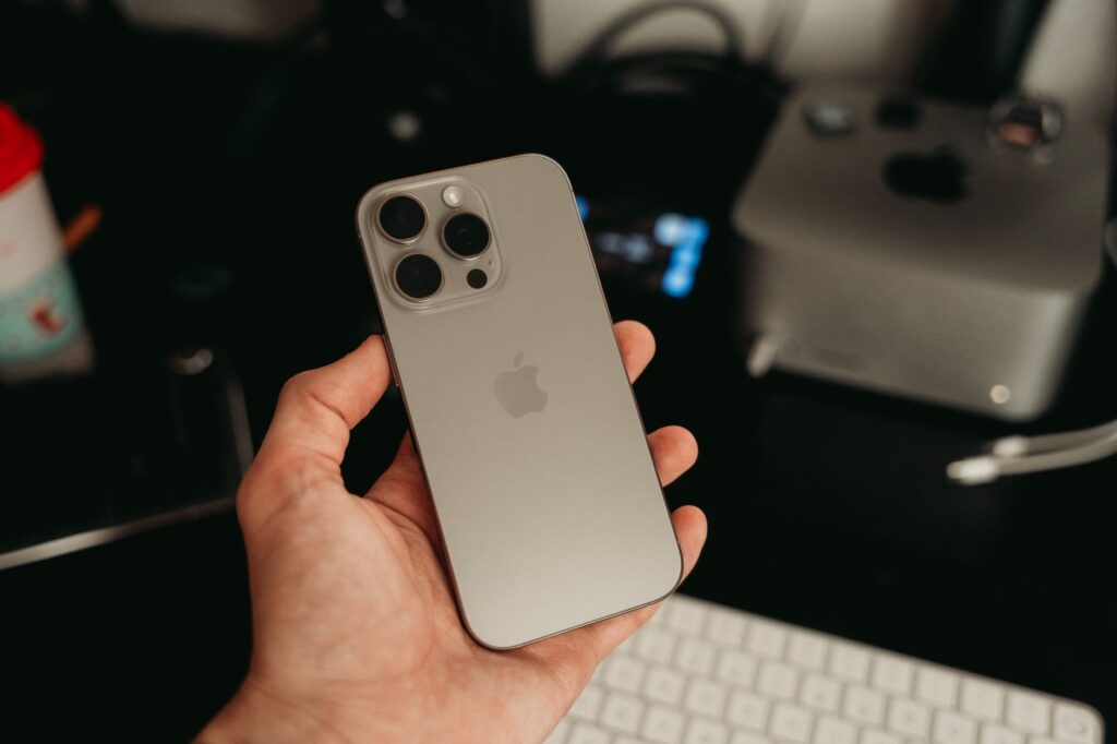 A hand holding a sleek smartphone in a tech-savvy office environment, showcasing its design.