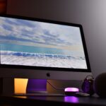 Apple iMac displaying ocean view. Elegant workspace with ambient lighting.