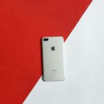 A silver smartphone placed on a contrasting red and white background captured from above.