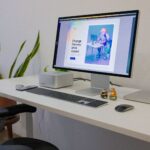 A sleek office setup featuring a desktop monitor, keyboard, and indoor plants, promoting a productive workspace.