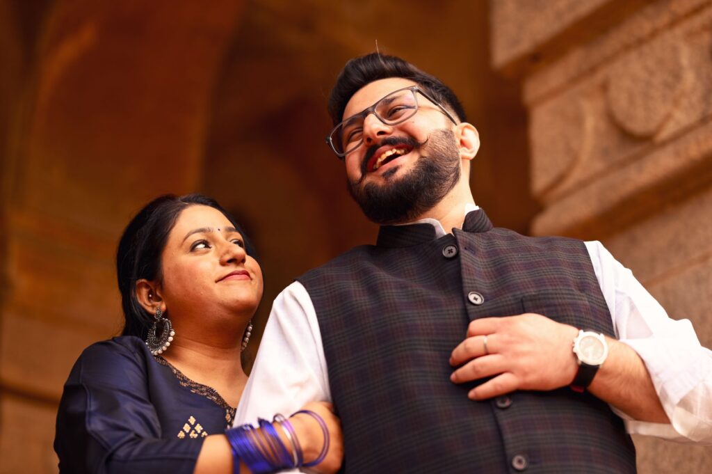 A joyful Indian couple embracing in traditional attire at a historical site in Delhi, India.