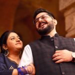 A joyful Indian couple embracing in traditional attire at a historical site in Delhi, India.