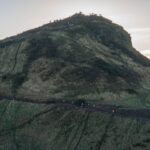 Scenic view of Arthur's Seat in Edinburgh with people hiking at sunset.