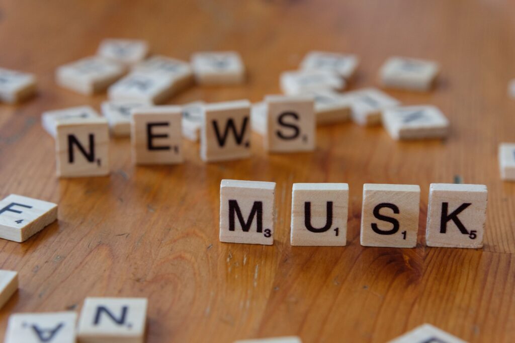 Close-up of wooden letter tiles on a table spelling 'News Musk', concept of media coverage.