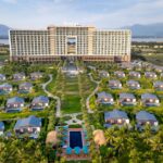 Aerial view of a luxury resort with bungalows surrounded by mountains and palm trees.
