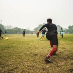 Energetic soccer game with players on a grassy field in India, showcasing teamwork and sportsmanship.